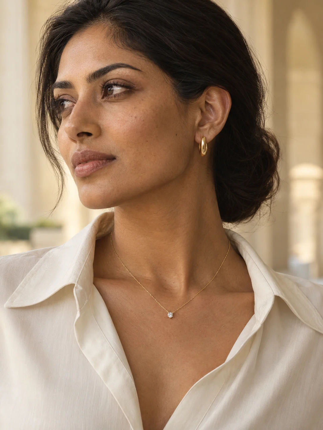 Gold hoops and a single-stone pendant worn with an ivory shirt